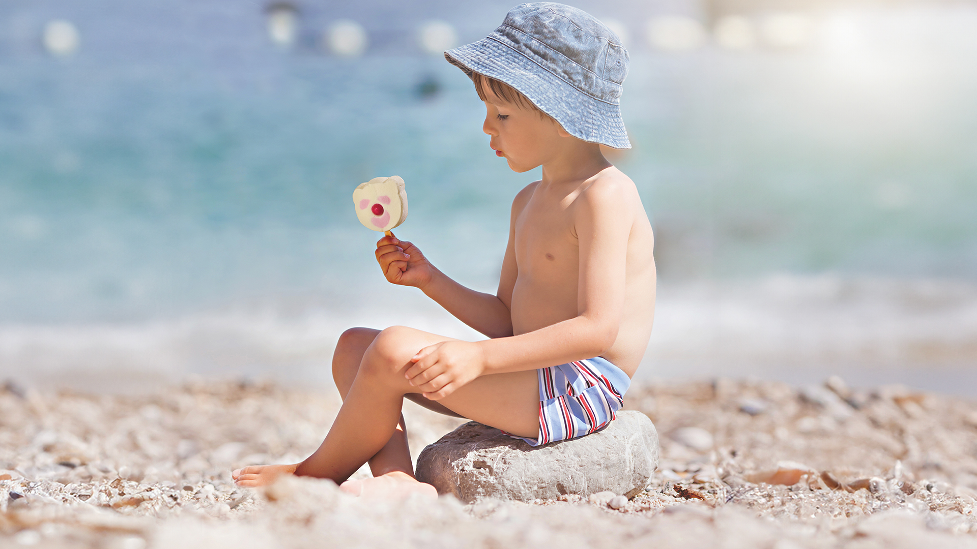 dreng-spiser-is-paa-stranden